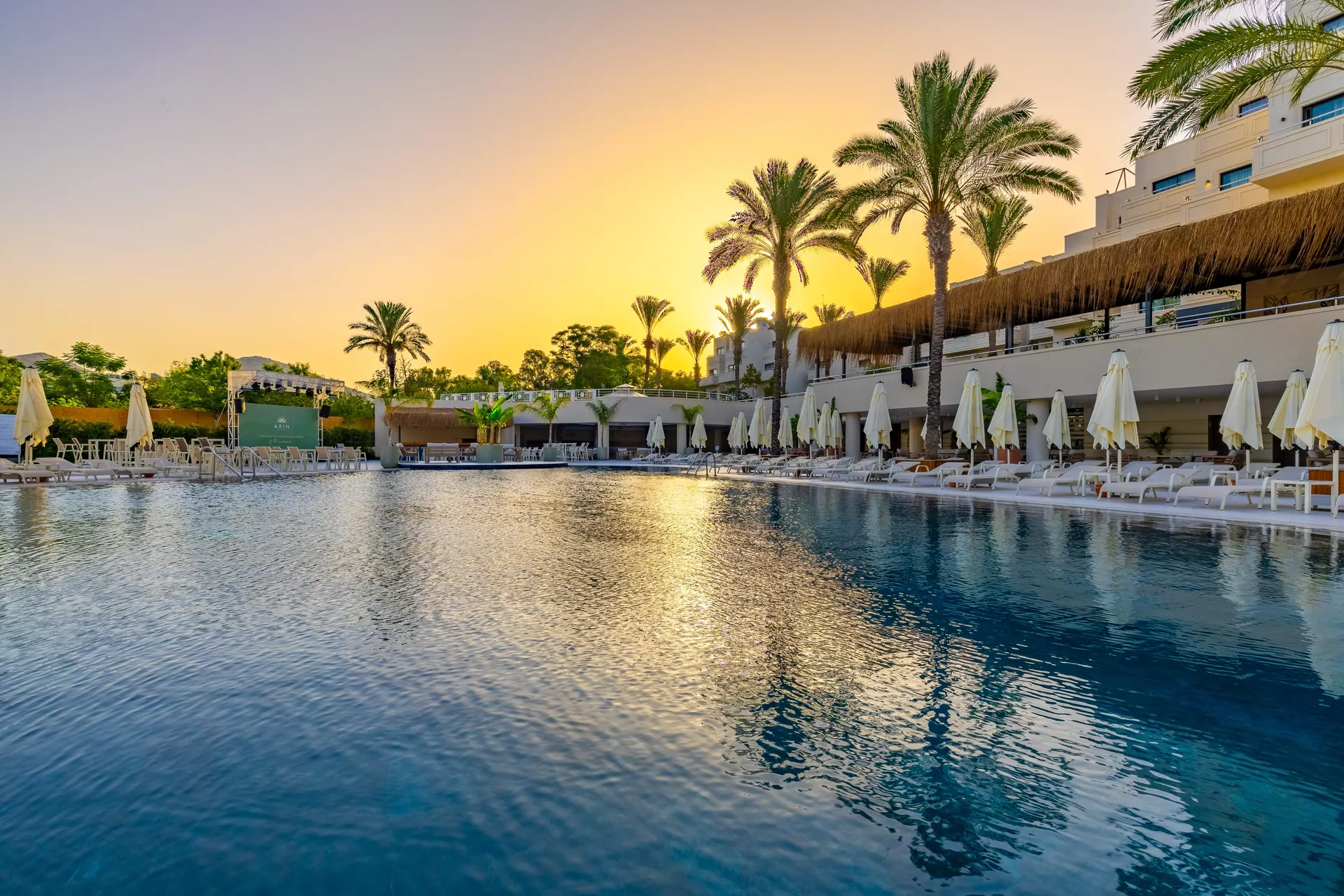 Gün batımında Arin Resort havuzu ve şezlonglar